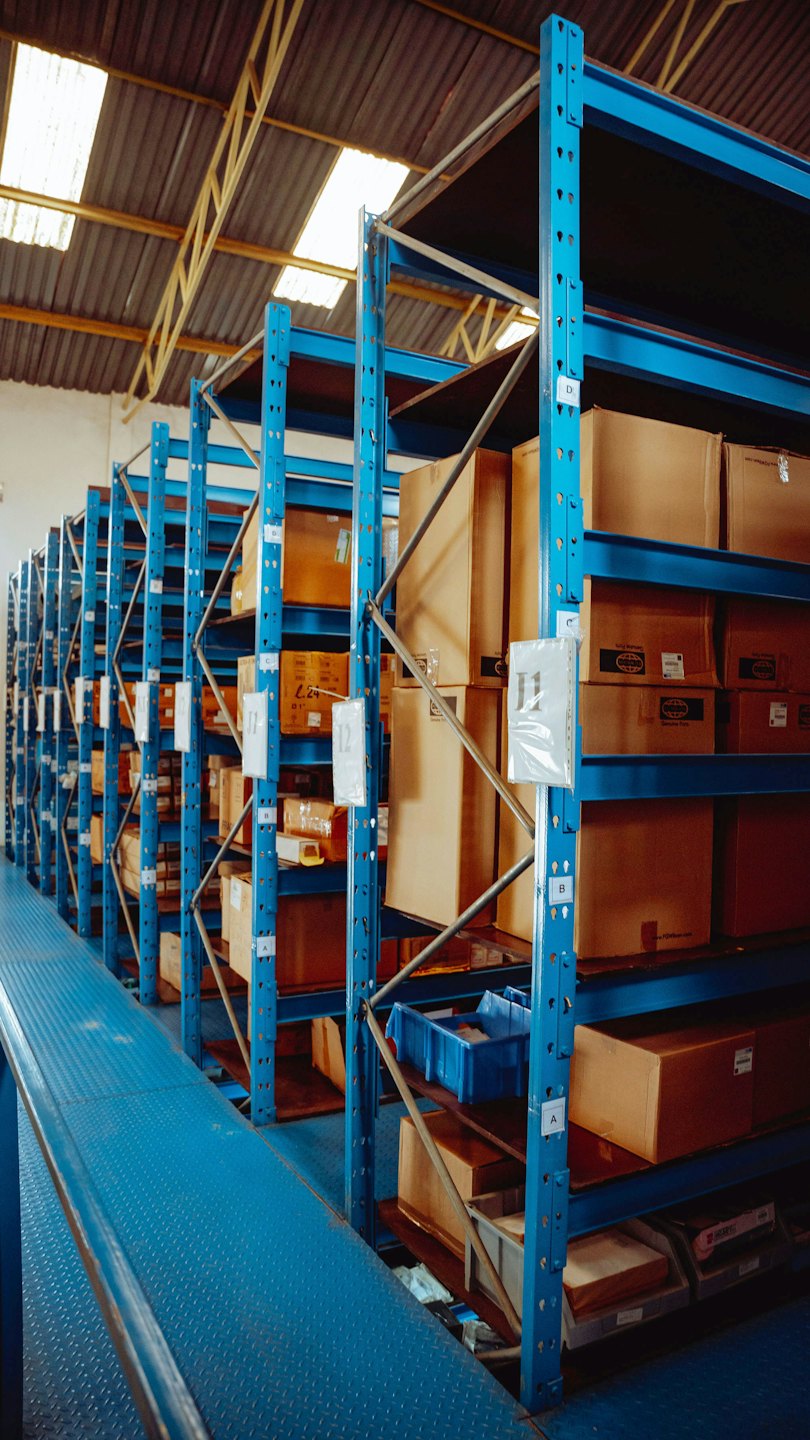 Warehouse aisle with tall blue shelving stacked with boxes.