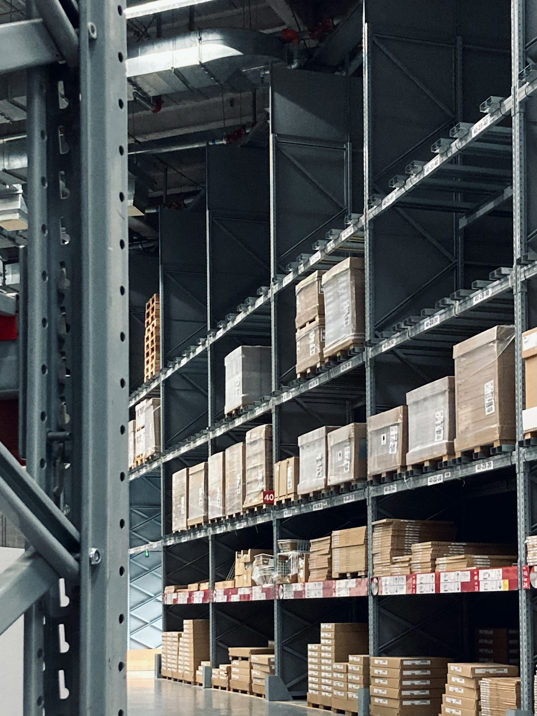 Rows of tall grey shelving units filled with boxes in a warehouse.