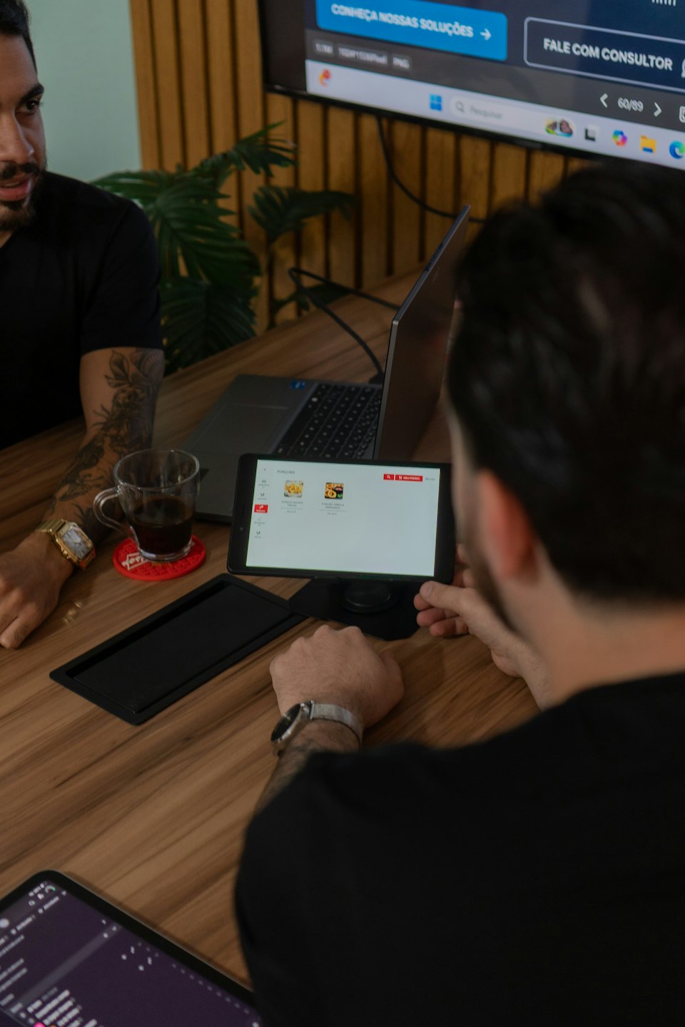 Two colleagues review a food ordering application on a tablet.